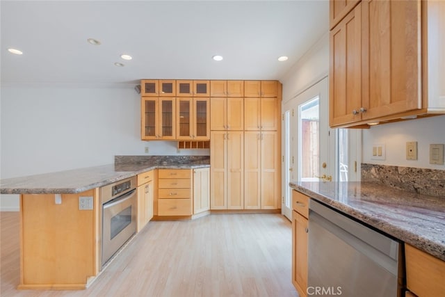 kitchen with a peninsula, stainless steel appliances, light wood-type flooring, recessed lighting, and glass insert cabinets