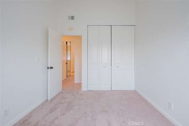 unfurnished bedroom featuring carpet, a closet, baseboards, and visible vents