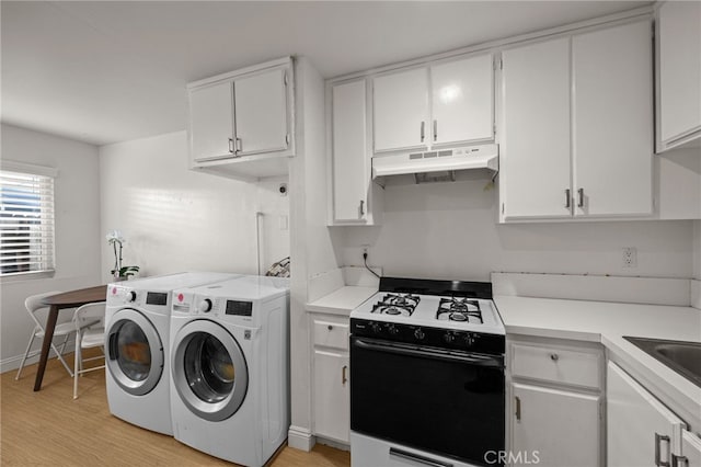 kitchen featuring washing machine and clothes dryer, light wood-style flooring, gas stove, and under cabinet range hood