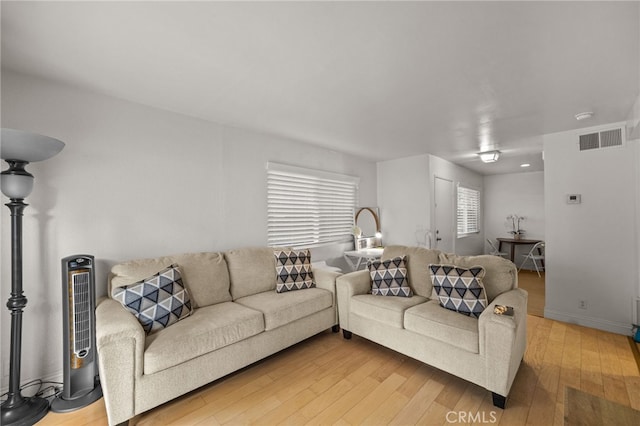 living area with baseboards, light wood finished floors, and visible vents