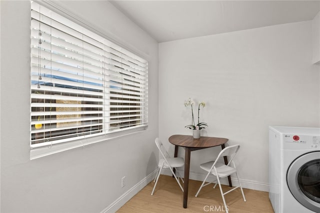 clothes washing area featuring washer / dryer, laundry area, plenty of natural light, and wood finished floors