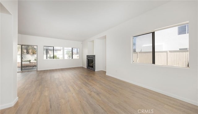 unfurnished living room featuring baseboards, a fireplace, and wood finished floors