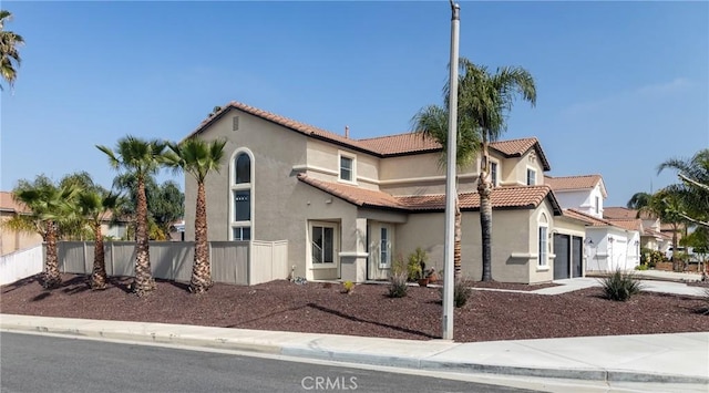 view of front of house featuring fence, an attached garage, stucco siding, and a tiled roof