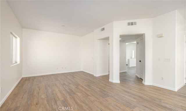 empty room featuring visible vents, wood finished floors, and baseboards