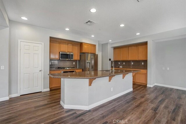 13167 Hollister St, Hesperia, CA 92344 - kitchen with stainless steel appliances, dark wood-style flooring, a center island with sink, a sink, and a breakfast bar area