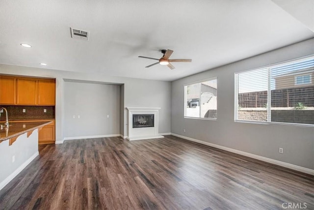 13167 Hollister St, Hesperia, CA 92344 - unfurnished living room with a ceiling fan, dark wood-type flooring, recessed lighting, a fireplace with raised hearth, and baseboards