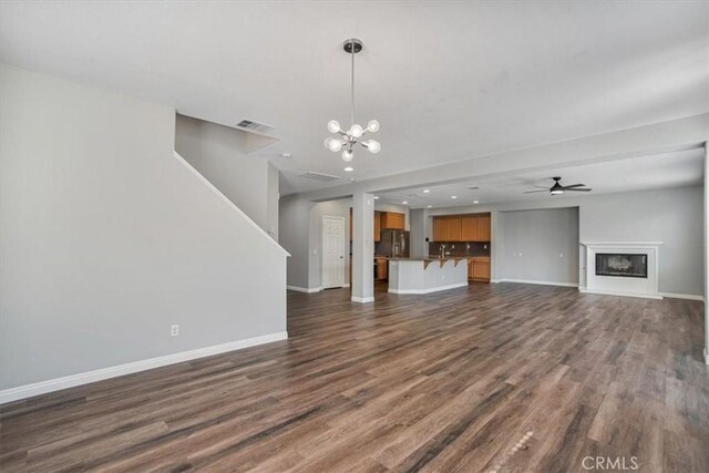 13167 Hollister St, Hesperia, CA 92344 - unfurnished living room featuring baseboards, dark wood-type flooring, a chandelier, a fireplace, and ceiling fan
