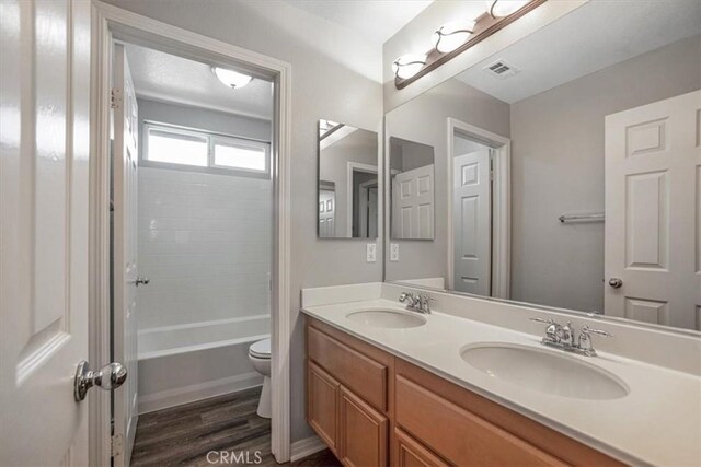 13167 Hollister St, Hesperia, CA 92344 - full bathroom featuring double vanity, toilet, wood finished floors, and washtub / shower combination