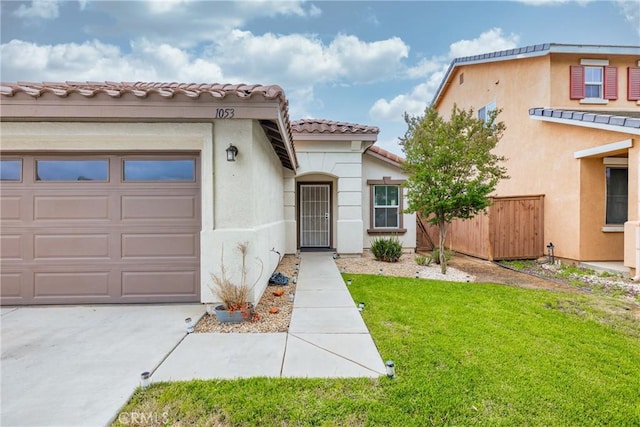 mediterranean / spanish-style home featuring a garage, a tiled roof, stucco siding, fence, and a front yard