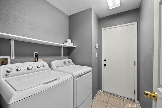 laundry room featuring laundry area, light tile patterned flooring, a textured wall, and washer and clothes dryer