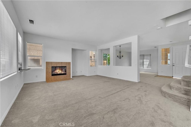 43629 Rucker Ct, Lancaster, CA 93535 - unfurnished living room featuring a tile fireplace, an inviting chandelier, visible vents, and light colored carpet