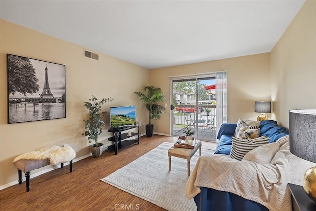 living room with baseboards, visible vents, and wood finished floors