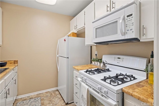 kitchen with white appliances, baseboards, light countertops, and white cabinets