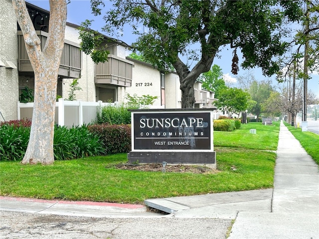 community / neighborhood sign with fence and a lawn
