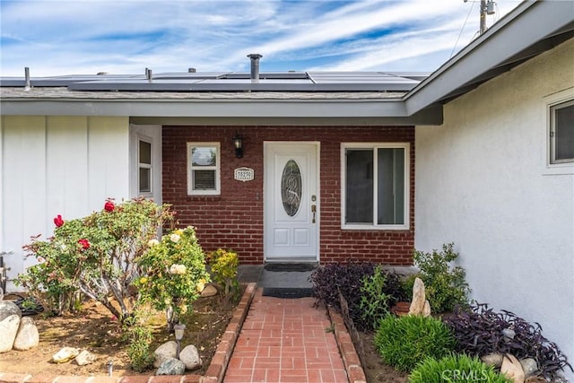 35230 San Carlos St, Yucaipa, CA 92399 - view of exterior entry featuring covered porch, roof mounted solar panels, and brick siding