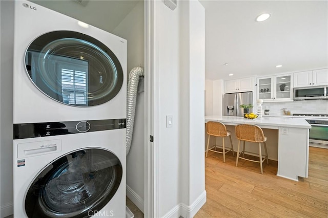 washroom with stacked washer / dryer, laundry area, recessed lighting, baseboards, and light wood-style floors
