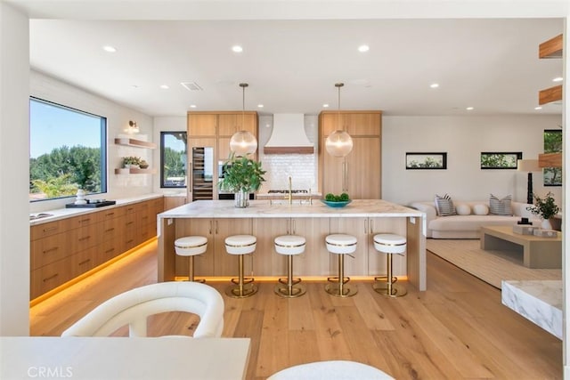 4 Sunset Cv, Newport Coast, CA 92657 - kitchen with light wood finished floors, open shelves, modern cabinets, light countertops, and custom range hood