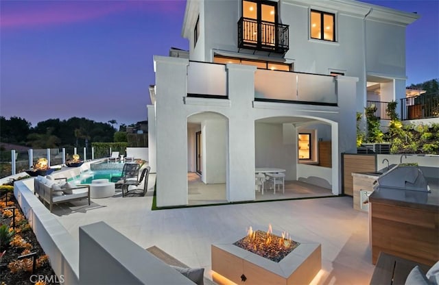 4 Sunset Cv, Newport Coast, CA 92657 - back of property at dusk with a patio area, a balcony, stucco siding, a fenced in pool, and an outdoor kitchen