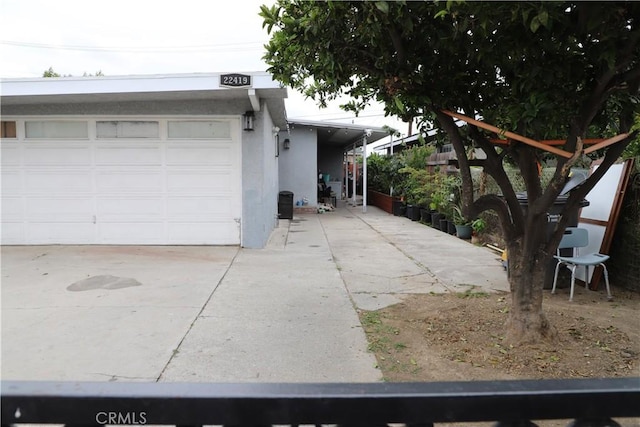 view of side of home featuring concrete driveway, stucco siding, and a garage