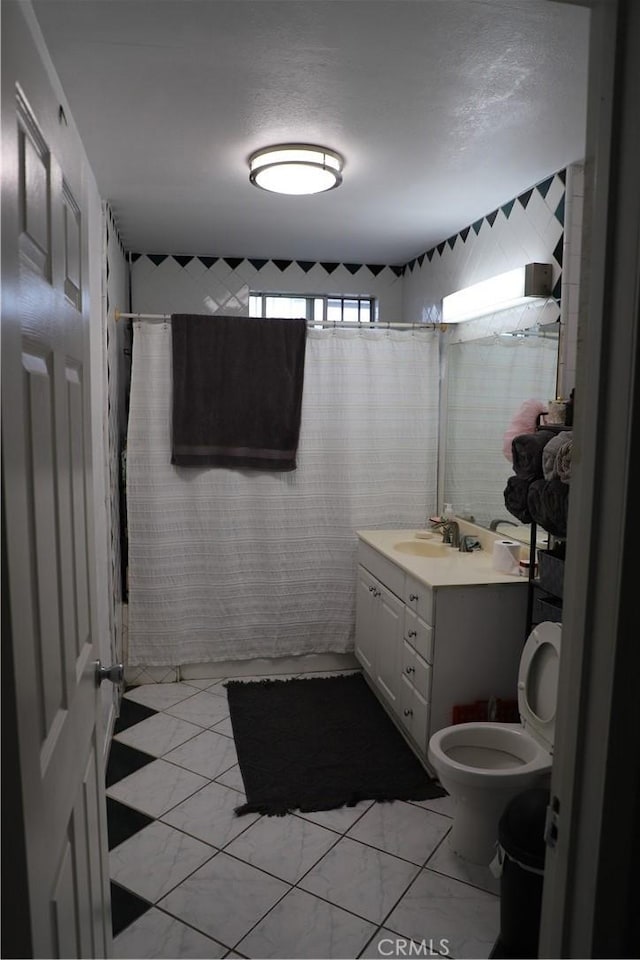 bathroom with toilet, marble finish floor, vanity, curtained shower, and a textured ceiling