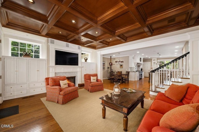 living area featuring a fireplace, crown molding, coffered ceiling, and wood finished floors