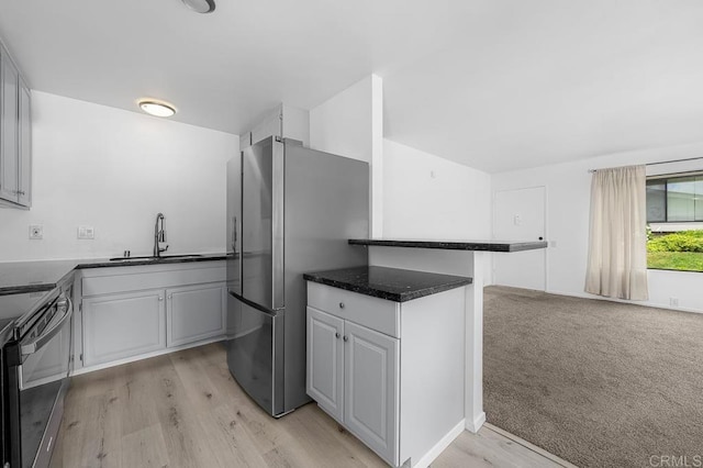 kitchen featuring freestanding refrigerator, light wood finished floors, a sink, white cabinetry, and black electric range
