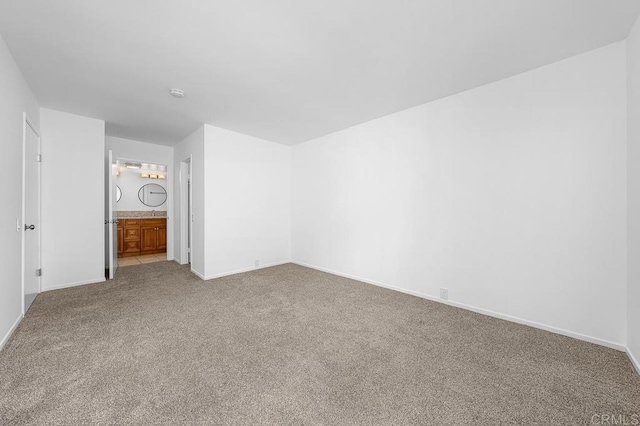 unfurnished bedroom featuring ensuite bathroom, carpet floors, and baseboards