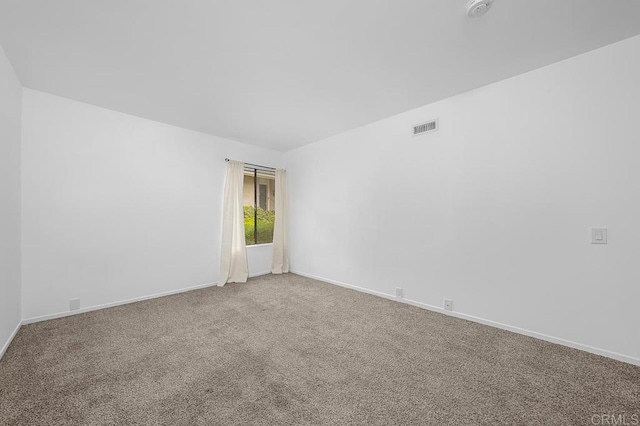 carpeted spare room featuring baseboards and visible vents