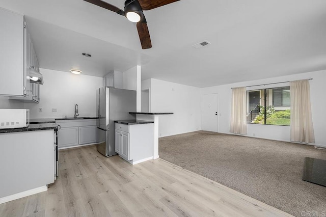 kitchen with freestanding refrigerator, ceiling fan, visible vents, white microwave, and dark countertops