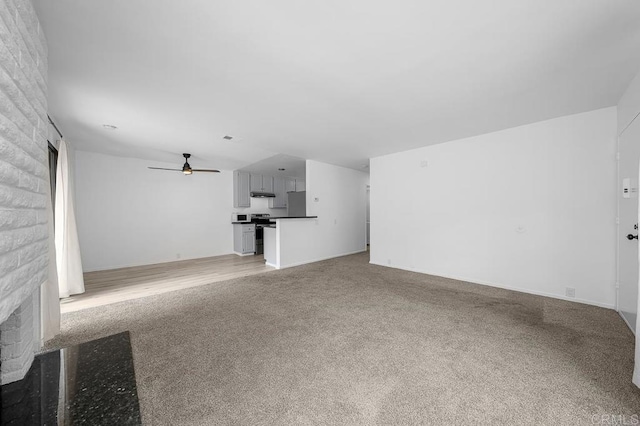 unfurnished living room with a brick fireplace, light carpet, and ceiling fan