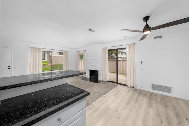 kitchen featuring light wood-type flooring, visible vents, and a brick fireplace