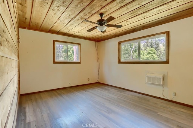empty room with wooden ceiling, light wood finished floors, an AC wall unit, and baseboards