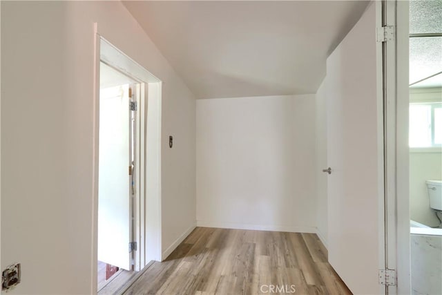 hall featuring light wood-type flooring and vaulted ceiling
