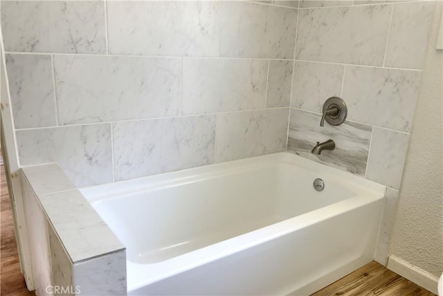 bathroom featuring a tub, wood finished floors, and baseboards