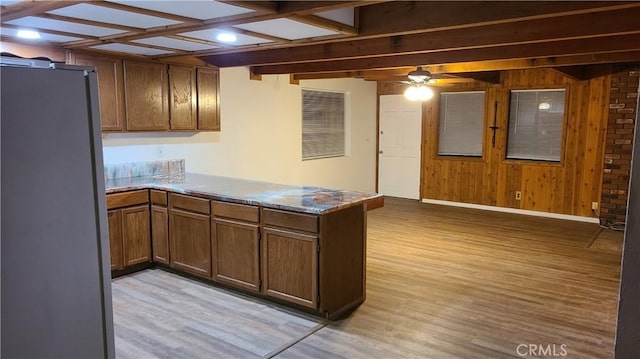 31194 Outer Highway 18 N, Running Springs, CA 92382 - kitchen with freestanding refrigerator, a peninsula, light wood-type flooring, wood walls, and a ceiling fan