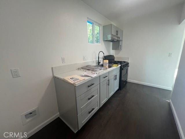 3001 N State St, San Bernardino, CA 92407 - kitchen with under cabinet range hood, baseboards, black gas stove, light countertops, and dark wood-style floors