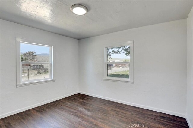 3001 N State St, San Bernardino, CA 92407 - spare room featuring baseboards, dark wood finished floors, and plenty of natural light
