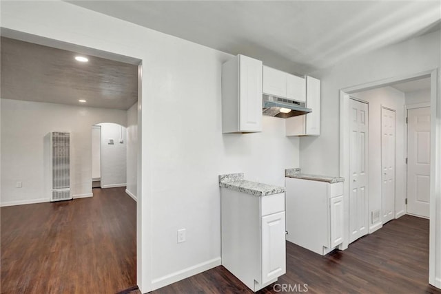 3001 N State St, San Bernardino, CA 92407 - kitchen featuring under cabinet range hood, dark wood-style flooring, white cabinetry, arched walkways, and a heating unit