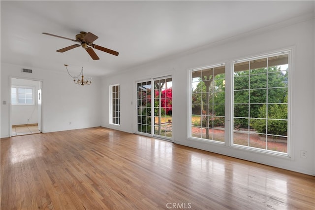 unfurnished room featuring ornamental molding, ceiling fan with notable chandelier, light wood-type flooring, and visible vents
