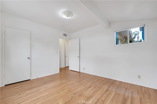 unfurnished bedroom with baseboards, light wood-type flooring, visible vents, and vaulted ceiling with beams