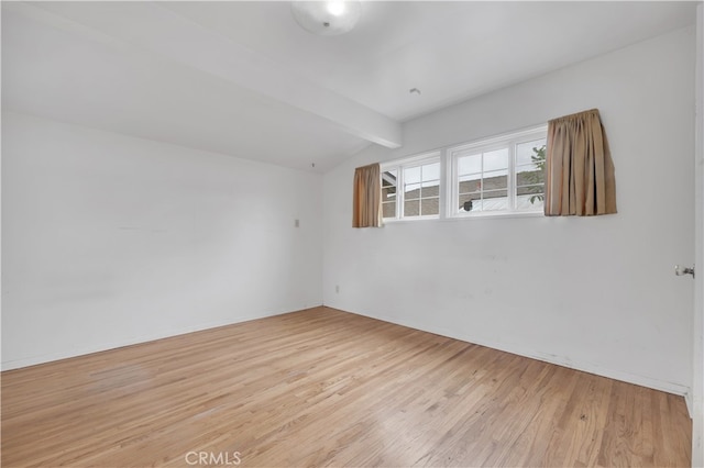 unfurnished room featuring light wood finished floors and lofted ceiling with beams
