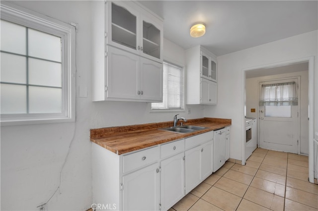 kitchen with a sink, white cabinets, glass insert cabinets, light tile patterned floors, and white dishwasher