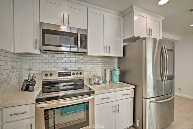 54345 Avenida Carranza Ln, Quinta, CA 92253 - kitchen with backsplash, baseboards, stainless steel appliances, and white cabinets