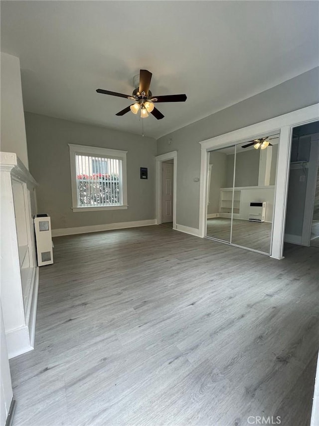 unfurnished living room featuring wood finished floors, baseboards, and ceiling fan
