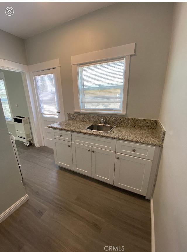 kitchen with a sink, light stone countertops, dark wood-style floors, and white cabinets