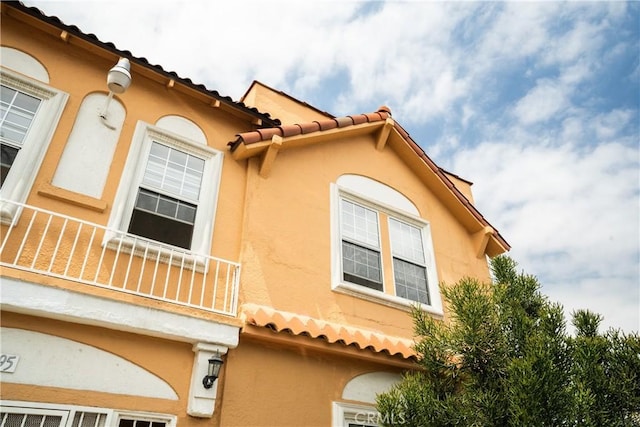 view of home's exterior featuring a balcony, stucco siding, and a tiled roof