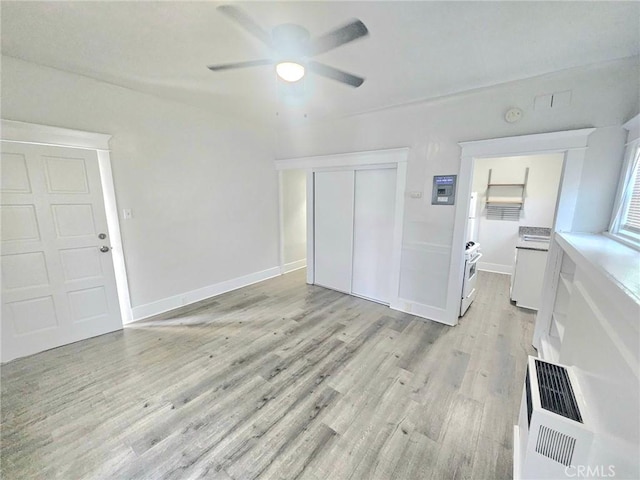 unfurnished living room featuring ceiling fan, baseboards, light wood finished floors, and washer and dryer