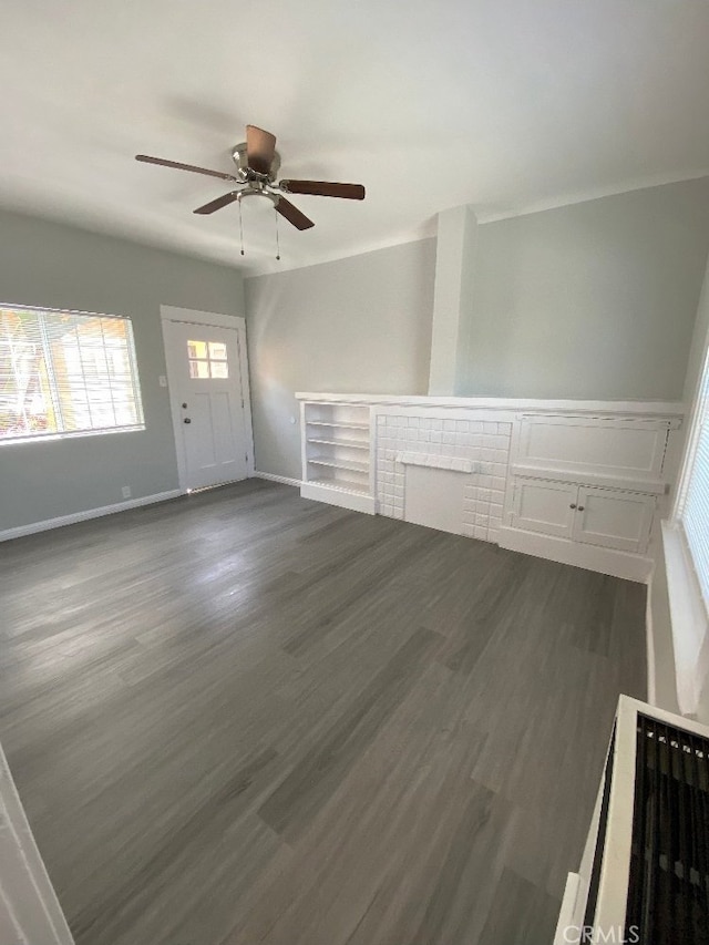 unfurnished living room with a ceiling fan, baseboards, and dark wood-style floors