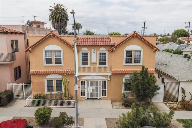 back of property featuring a tile roof, stucco siding, a gate, and fence private yard