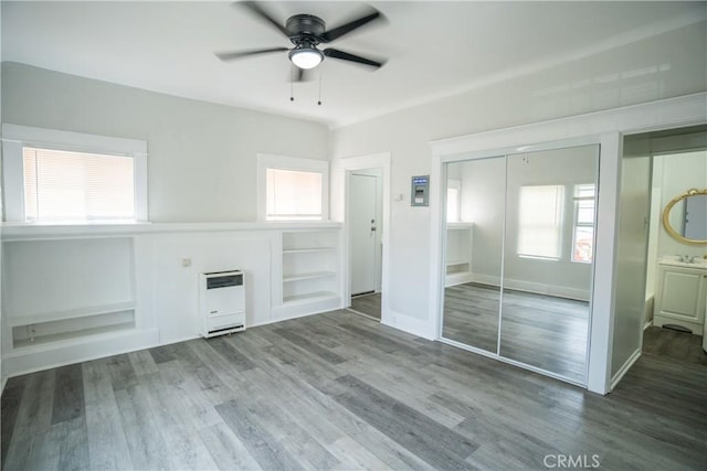 unfurnished living room featuring a sink, ceiling fan, heating unit, and wood finished floors